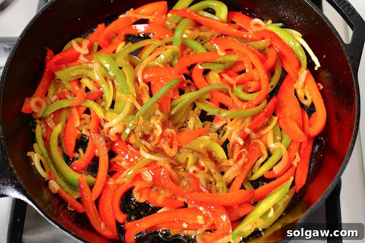Sizzling Chicken Fajitas 6 Bell peppers and onions cooking with marinade in a hot skillet, beginning to soften and caramelize.