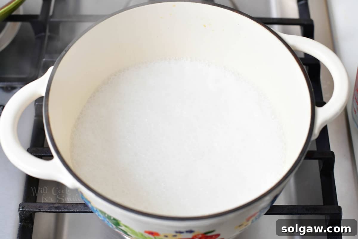 Fragrant Coconut Rice 4 The ingredients, except for rice, are combined in a large pot on the stovetop, being whisked together.