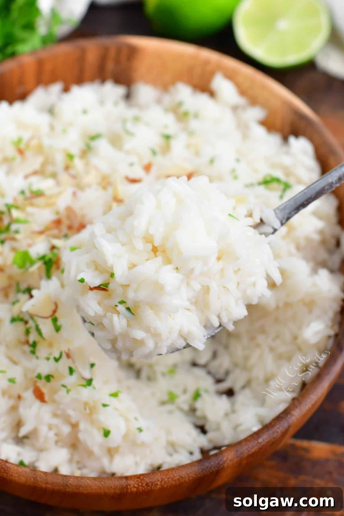 Fragrant Coconut Rice 7 Fluffed coconut rice on a fork, lifting a small portion from a wooden bowl, demonstrating its perfect texture.