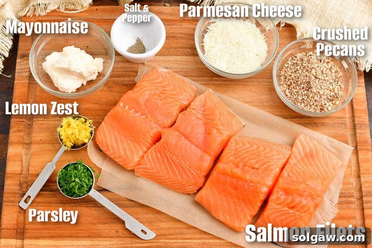 Labeled ingredients, including fresh salmon fillets, pecans, Parmesan, lemon, and parsley, are neatly arranged on a wooden board.