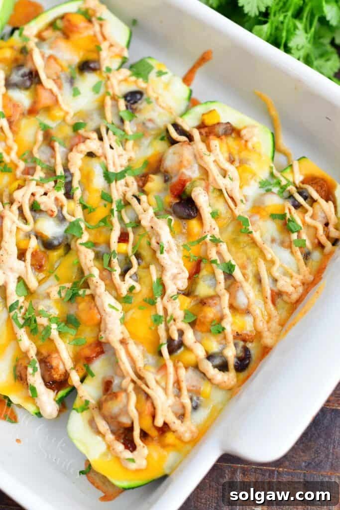 Zesty Southwest Chicken Zucchini Boats 2 Closer view of perfectly baked Southwest Chicken Zucchini Boats in a white baking dish, showcasing melted cheese and colorful filling.