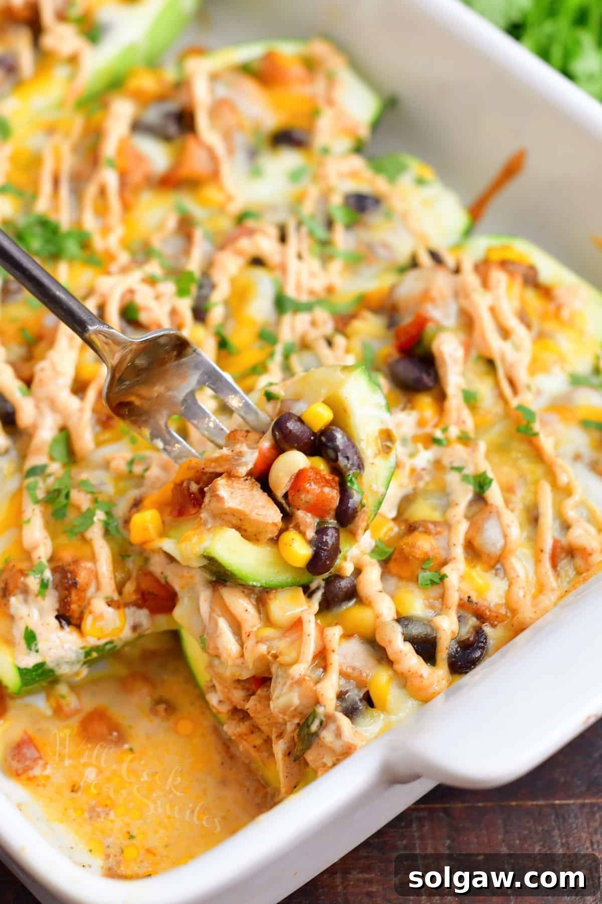 Closeup of a cut zucchini boat piece on a fork, showing the delicious filling.