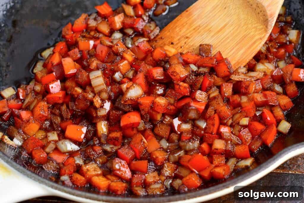 Zesty Southwest Chicken Zucchini Boats 6 Cooked diced onions and bell peppers in a pan, softened and flavorful.