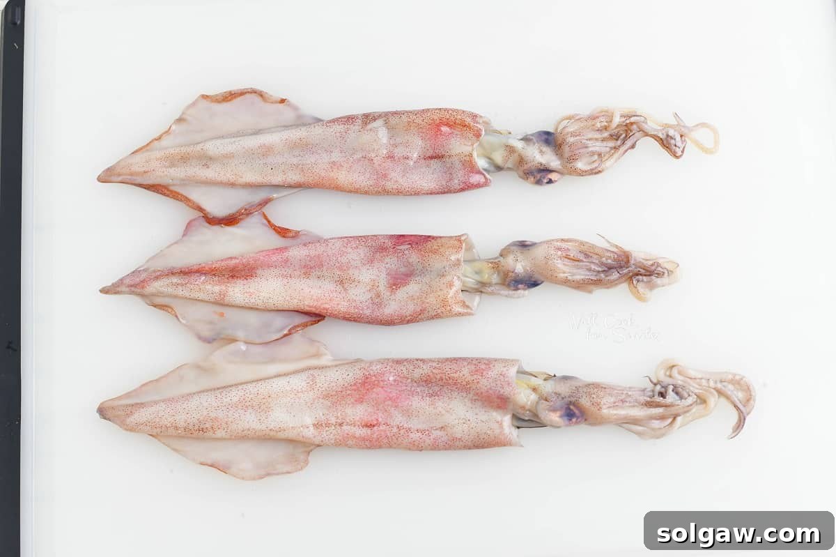 three whole squid on a cutting board