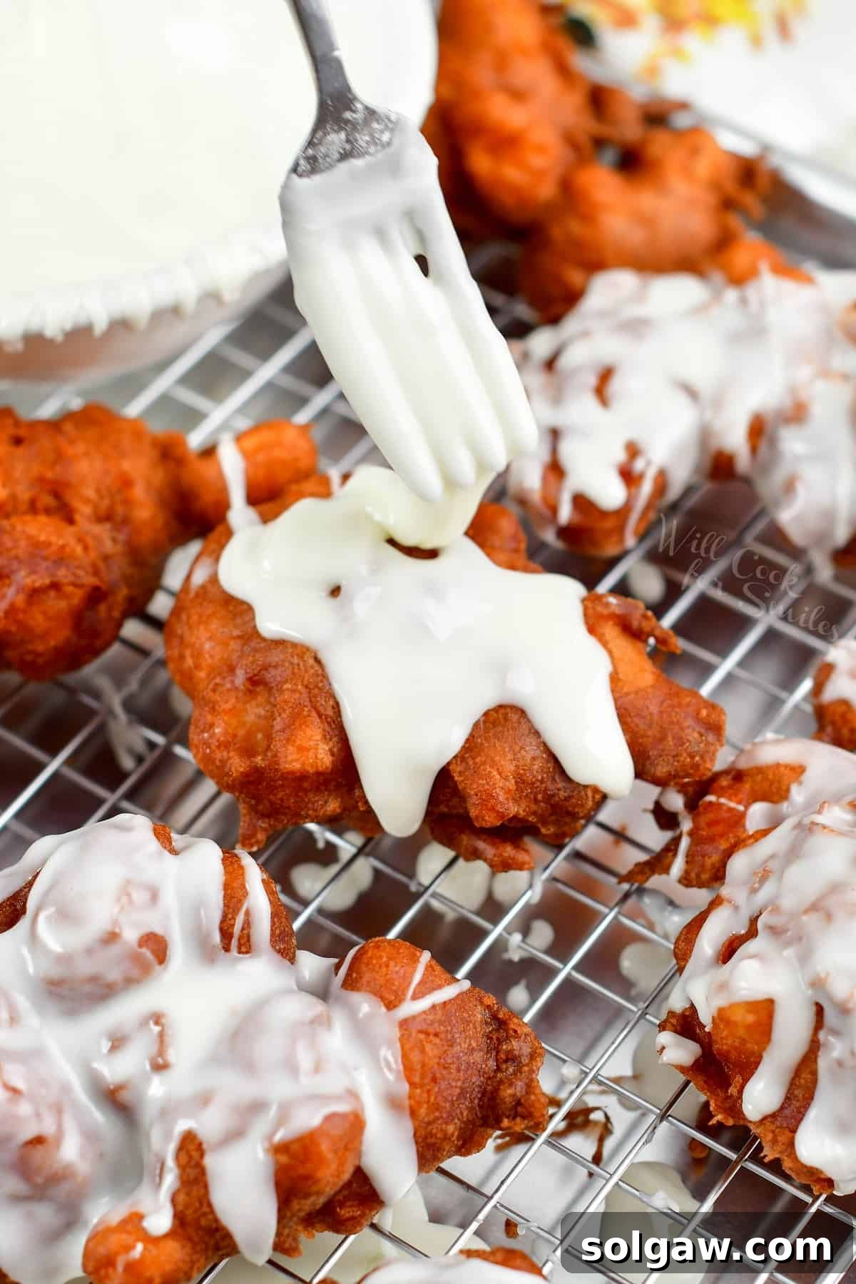 Golden Apple Delights 7 Drizzling vanilla icing generously on top of a hot apple fritter.