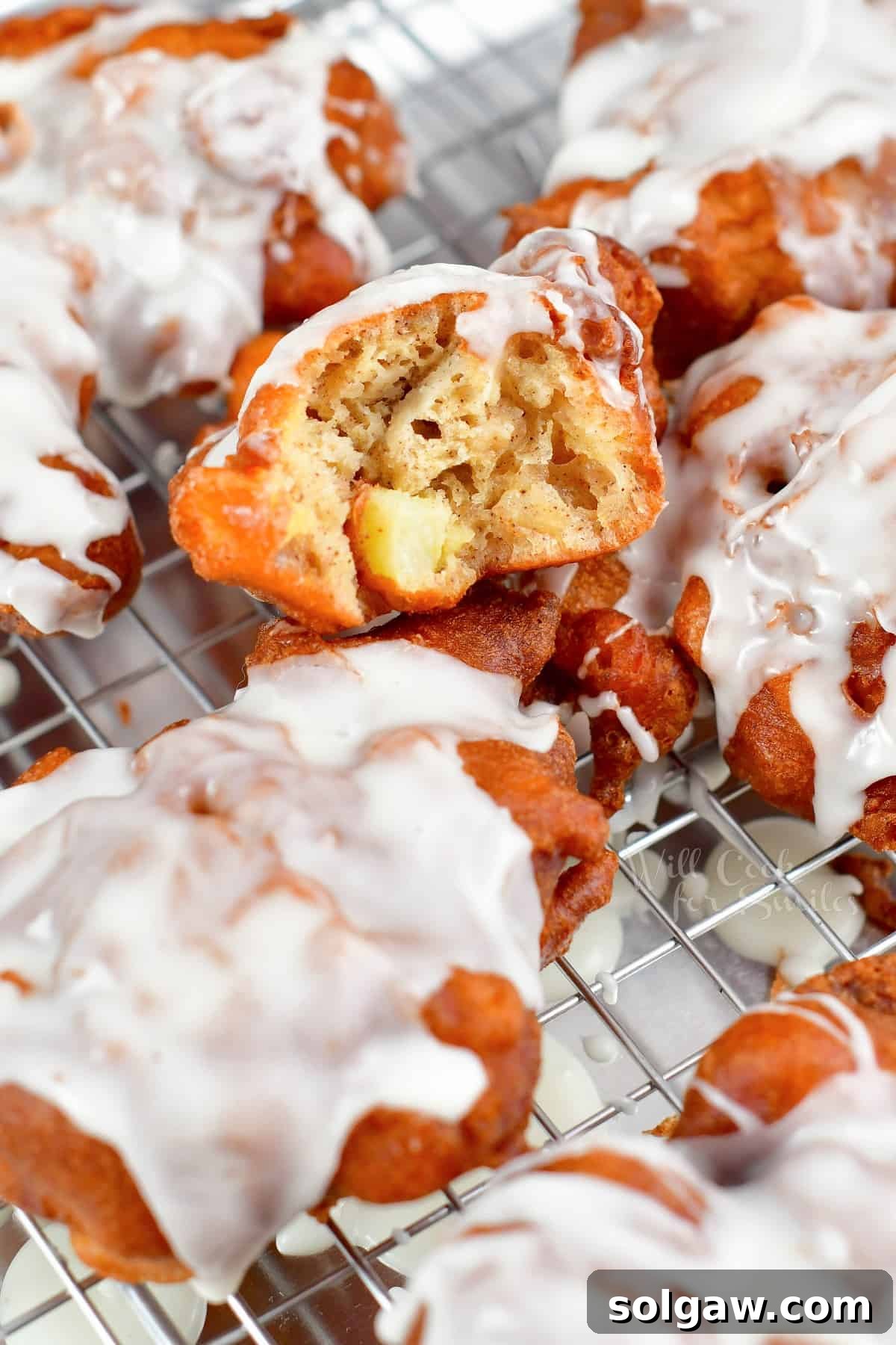 Golden Apple Delights 8 An apple fritter cut in half, showcasing its tender, apple-filled interior, resting on another fritter.