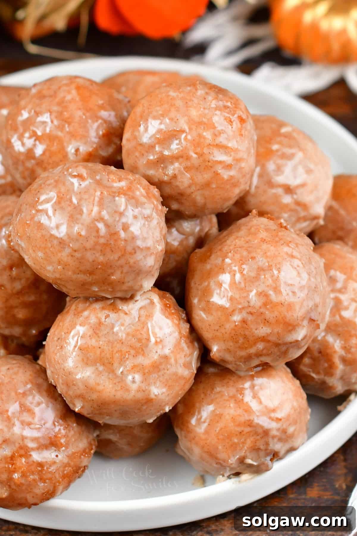 Closeup of stacked iced doughnut holes on a plate.