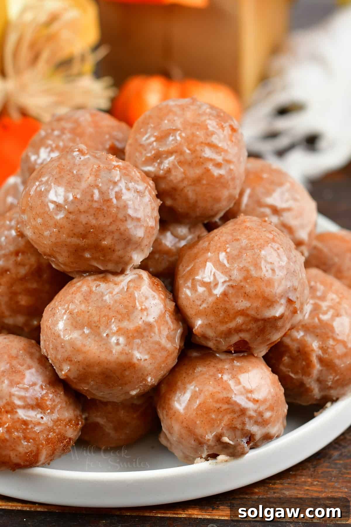 Stack of iced doughnut holes on a plate.