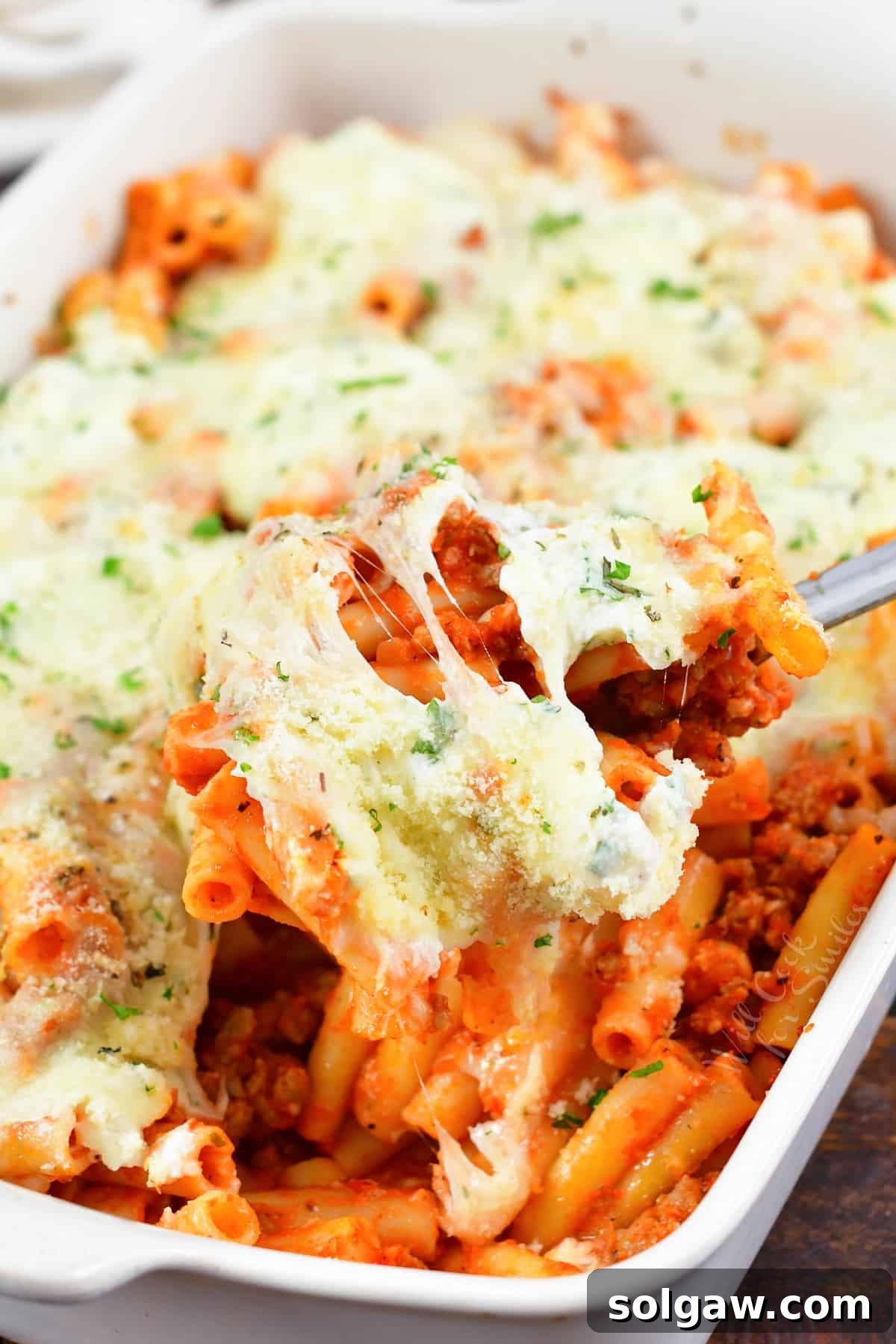 Delicious Baked Ziti being scooped from a casserole dish, with melted cheese stretching enticingly