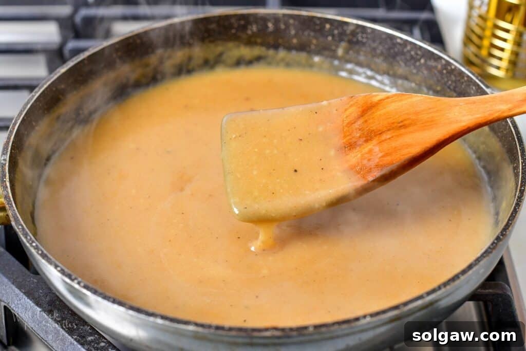 Homemade Poutine Perfection 12 stirring gravy in a deep cooking pan