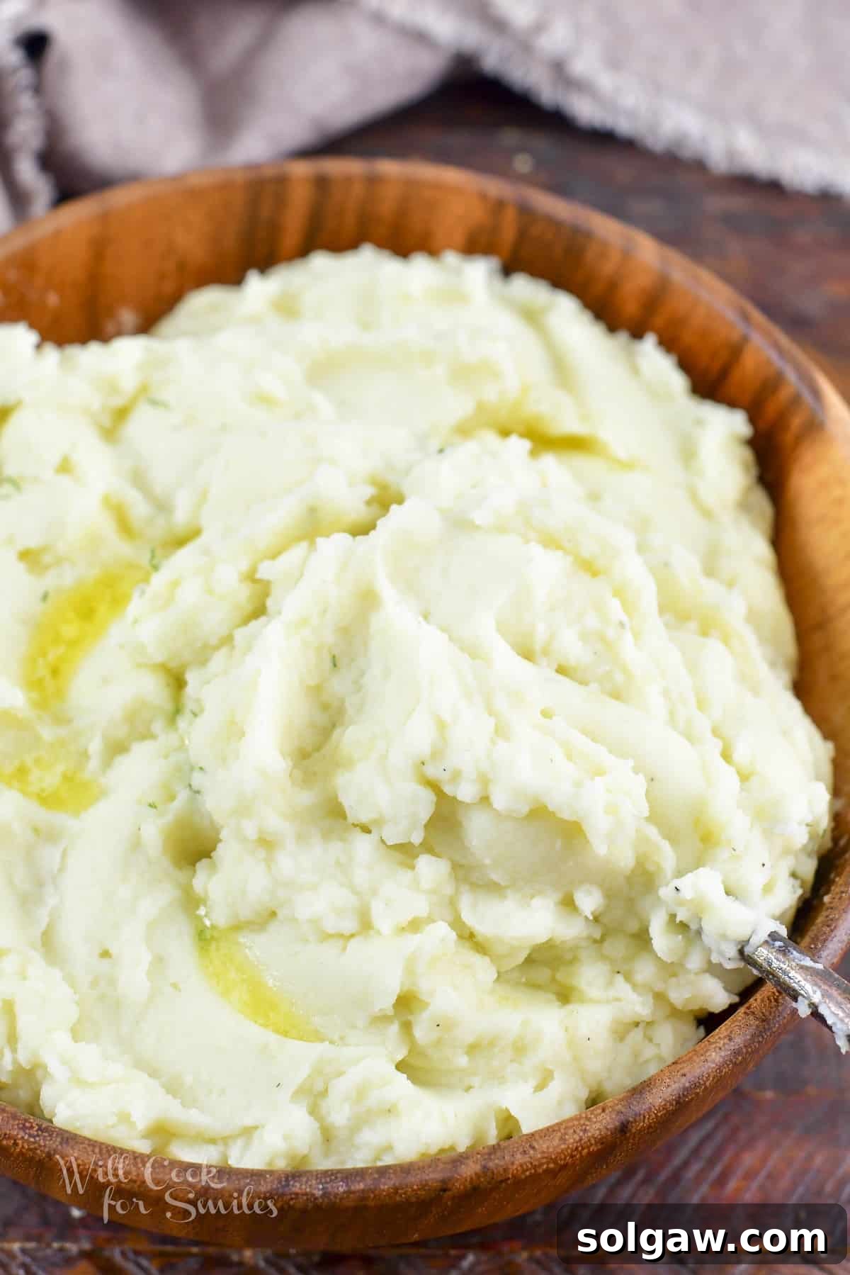 Perfectly Creamy Homemade Mashed Potatoes 2 scooping some perfectly smooth and fluffy mashed potatoes out of the wooden bowl.