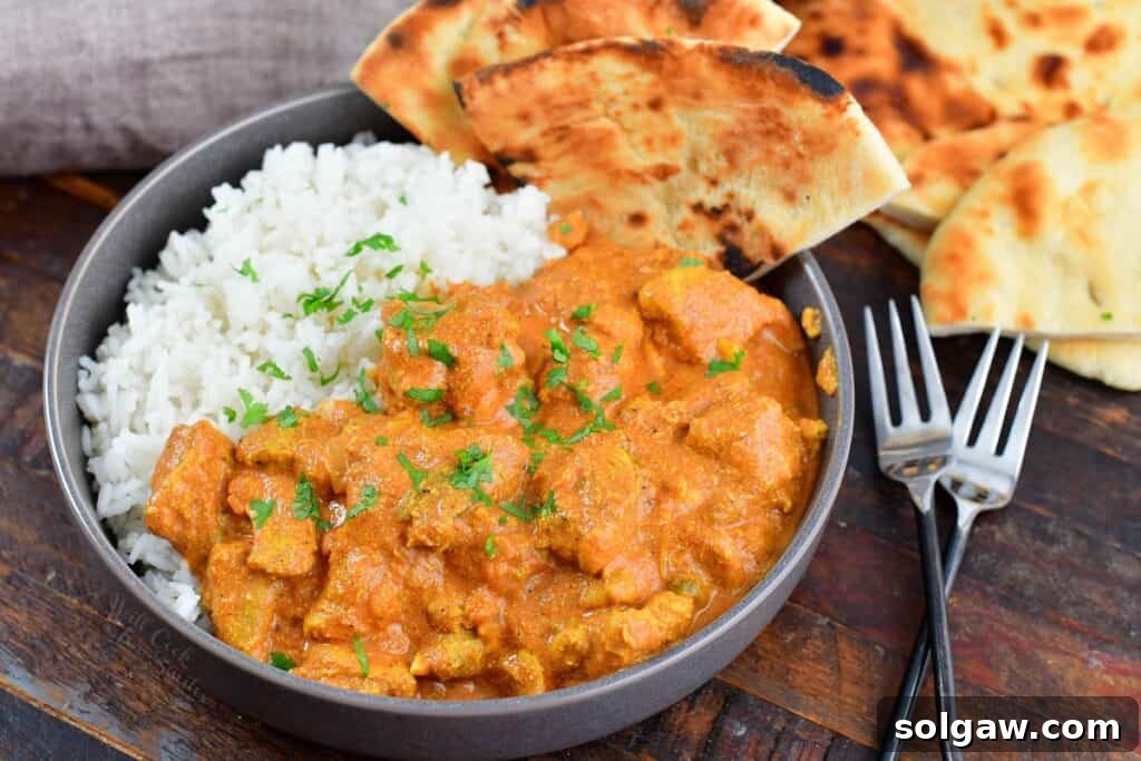 Butter Chicken Murgh Makhani 12 A vibrant bowl of homemade butter chicken served over fluffy rice, accompanied by soft naan bread.