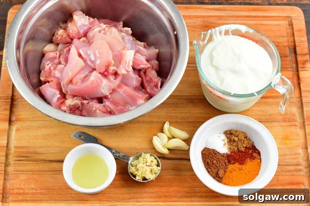 Butter Chicken Murgh Makhani 3 A collection of fresh ingredients laid out for butter chicken marinade, including yogurt, lemon, ginger, garlic, and colorful spices.