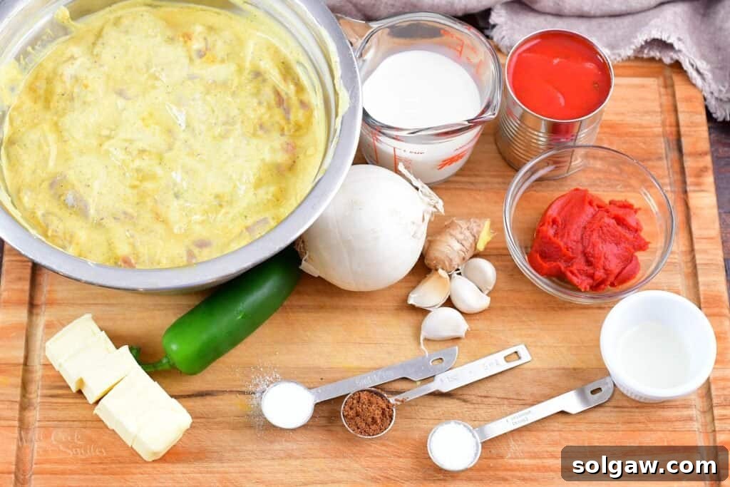 Butter Chicken Murgh Makhani 4 Fresh ingredients for butter chicken sauce beautifully arranged on a wooden cutting board, including onions, jalapeño, ginger, garlic, tomatoes, and spices.