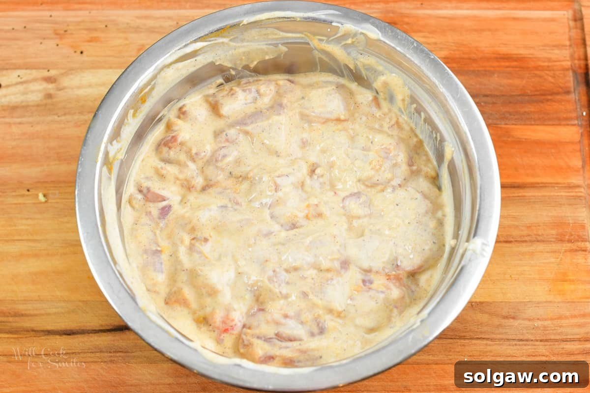 Butter Chicken Murgh Makhani 5 Cubed chicken marinating in a vibrant spiced yogurt mixture in a bowl, ready for cooking.