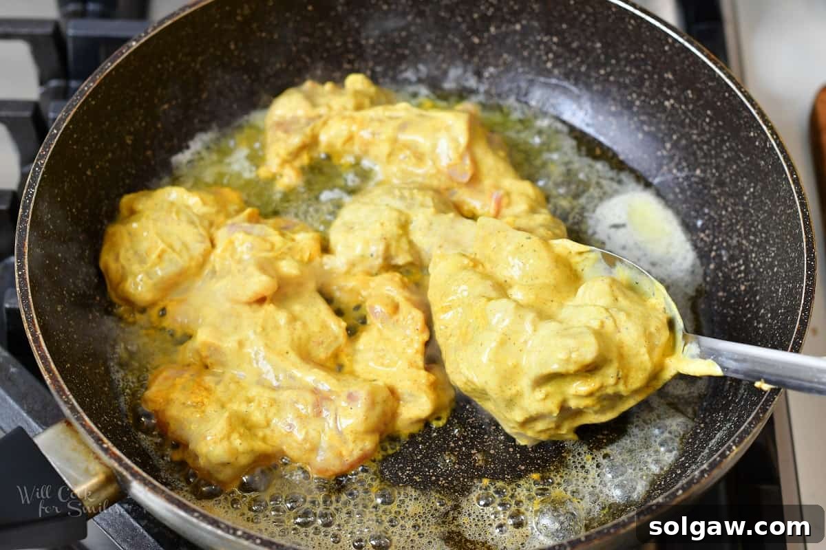 Butter Chicken Murgh Makhani 6 Searing marinated chicken pieces in a hot pan, creating a golden-brown crust.