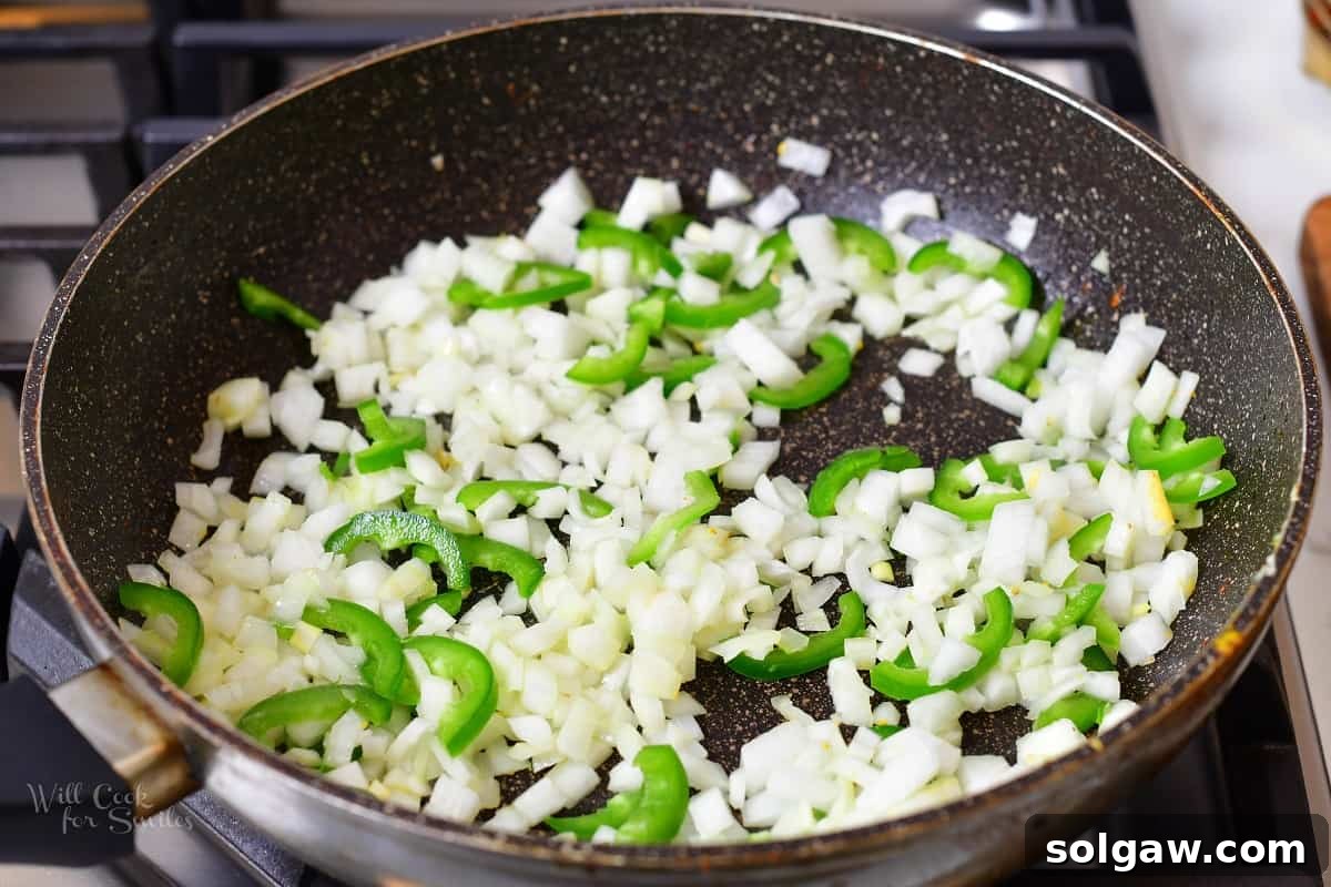 Butter Chicken Murgh Makhani 7 Onions and jalapeños sizzling in a pan with melted butter, beginning to soften.