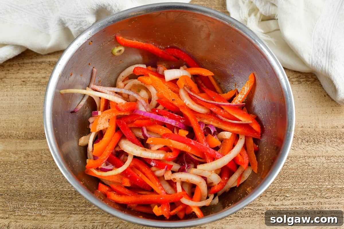 Zesty Air-Fried Southwest Chicken Thighs 6 Sliced red onions and bell peppers tossed with reserved marinade in a bowl.