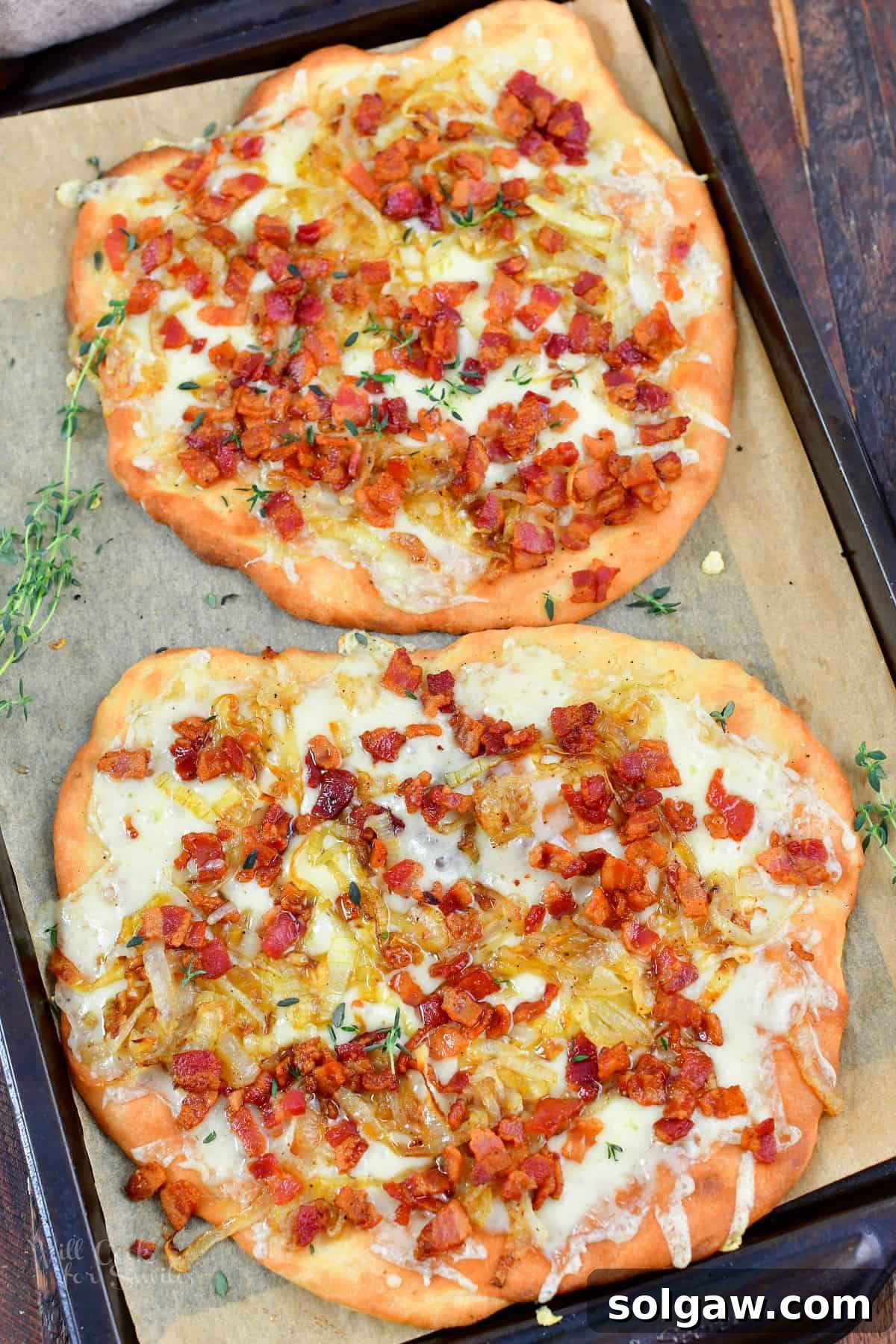 Sweet Golden Onion Smoky Bacon Gruyere Flatbread 14 top view of two baked flatbread pizzas on baking sheet, ready to be sliced and served
