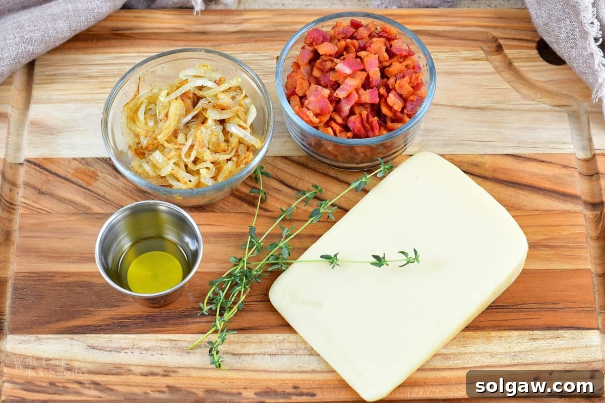 Sweet Golden Onion Smoky Bacon Gruyere Flatbread 4 ingredients for the flatbread topping on a cutting board: shredded Gruyere, cooked bacon bits, sliced caramelized onions, fresh thyme, salt, pepper