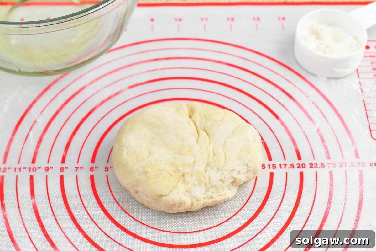 Sweet Golden Onion Smoky Bacon Gruyere Flatbread 6 kneaded pizza dough resting on a silicone mat, showing its smooth and pliable texture