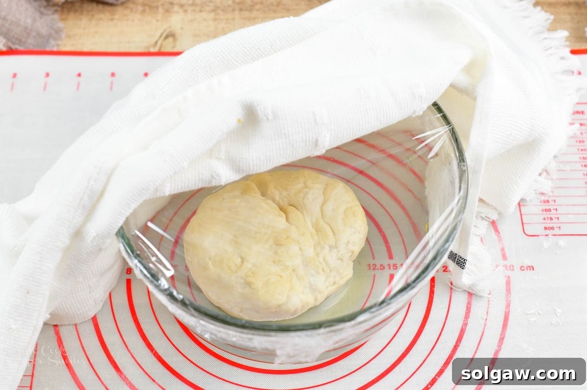 Sweet Golden Onion Smoky Bacon Gruyere Flatbread 7 dough in the glass bowl covered in plastic wrap and towel, ready for rising in a warm place