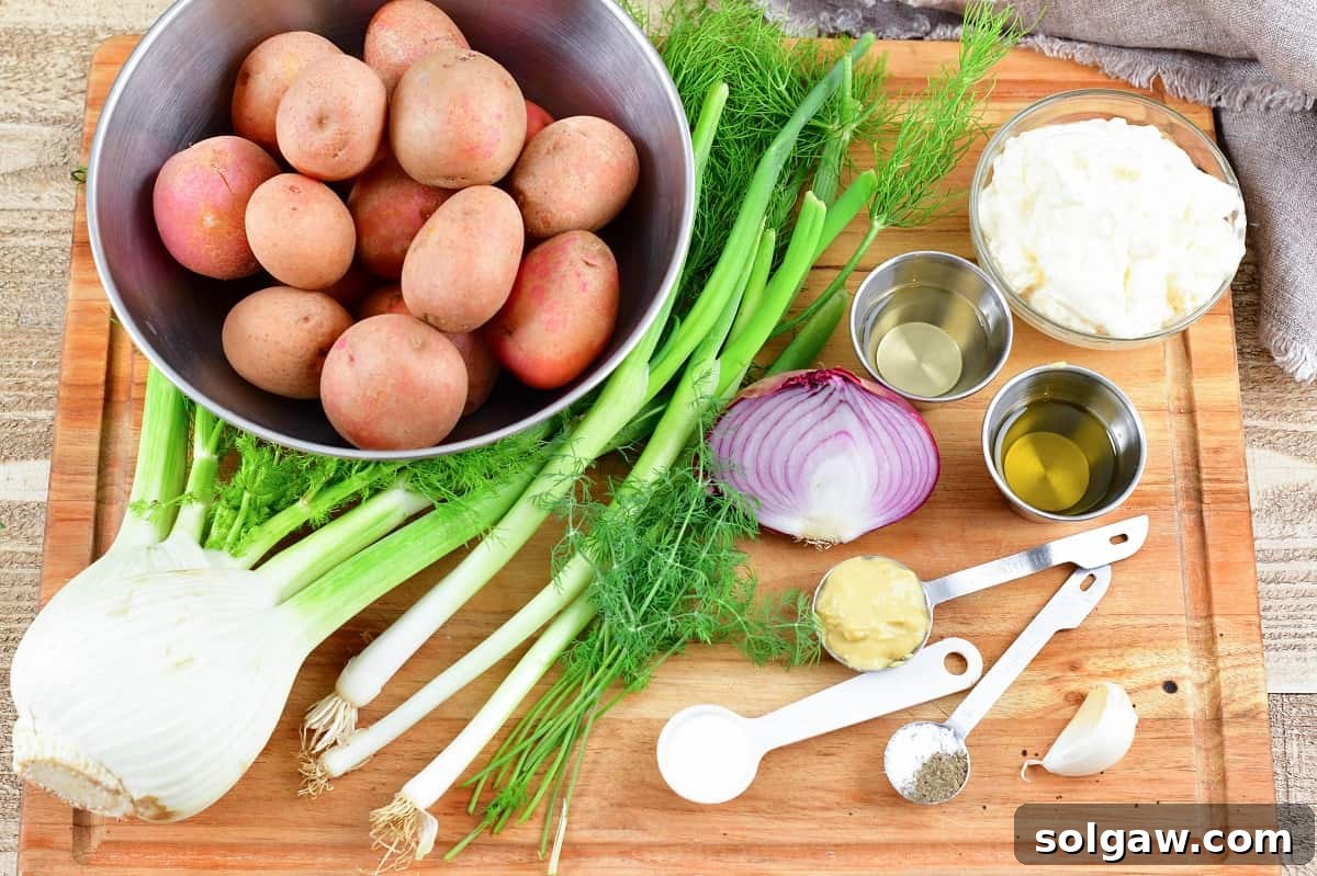 Ingredients for fennel potato salad laid out on a wooden cutting board, including new red potatoes, fresh fennel, green onions, and dill.