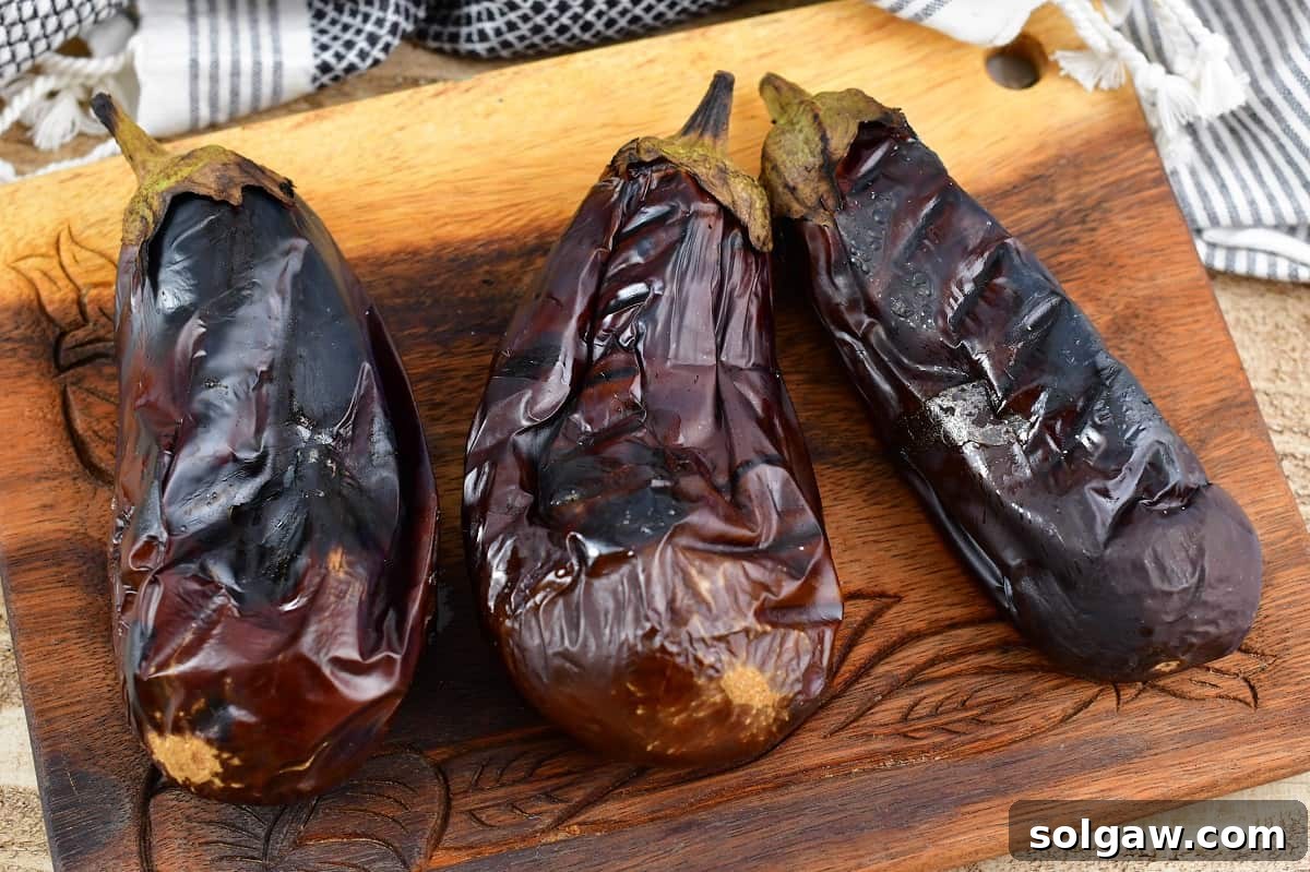 Smoky Aubergine Mezze 6 Three perfectly roasted eggplants resting on a wooden cutting board