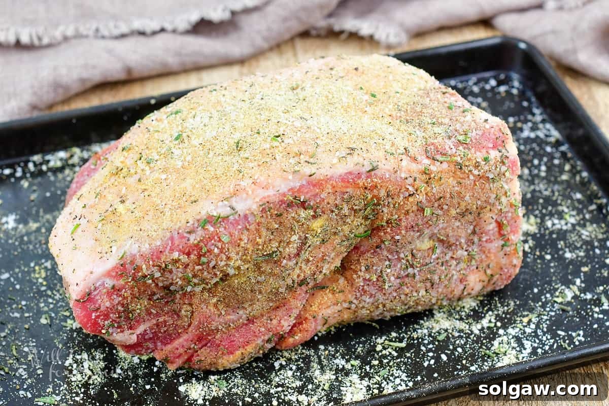 seasoned pork shoulder on the black metal baking sheet.