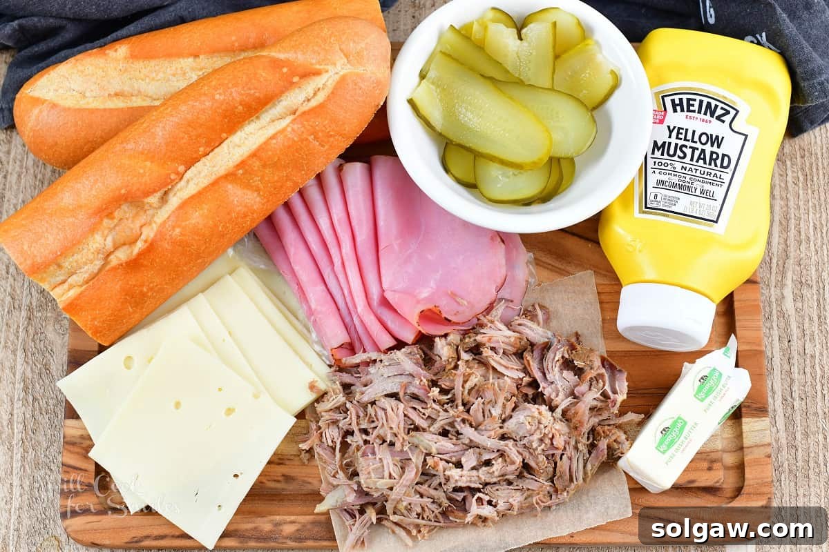 ingredients to make Cuban sandwiches, including bread, mustard, cheese, ham, pork, and pickles