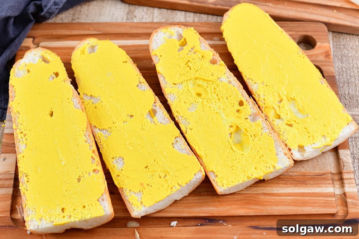 four halves of Cuban bread brushed with mustard, ready for assembly