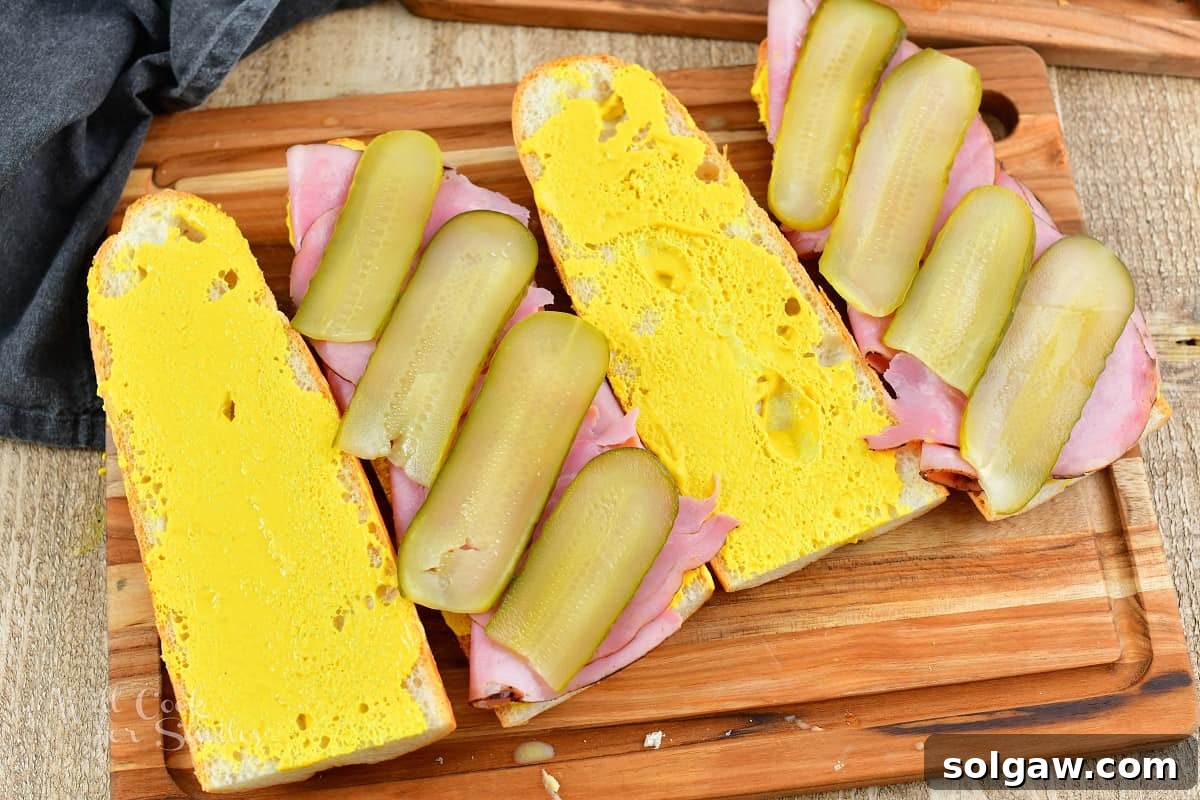 four slices of bread, two topped with ham and pickles for a Cuban sandwich
