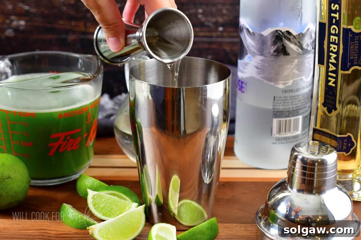 Adding St. Germain elderflower liqueur to a cocktail shaker.