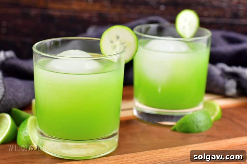 Closeup of two bright green cucumber cocktails garnished with cucumber slices.