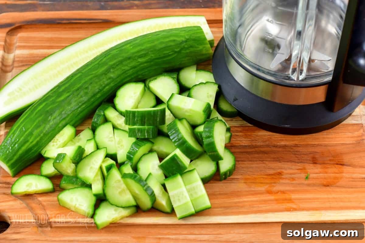 Chopped cucumbers ready for blending next to a blender.