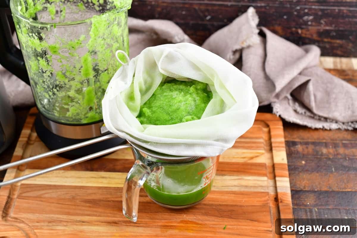 Blended cucumber being strained through a mesh bag.