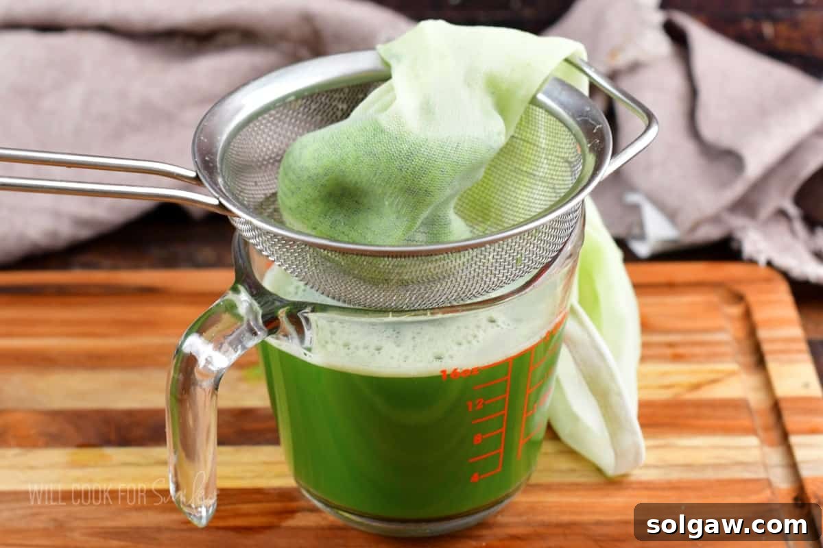 Cucumber juice collected in a measuring cup, with cucumber pulp in a mesh bag.