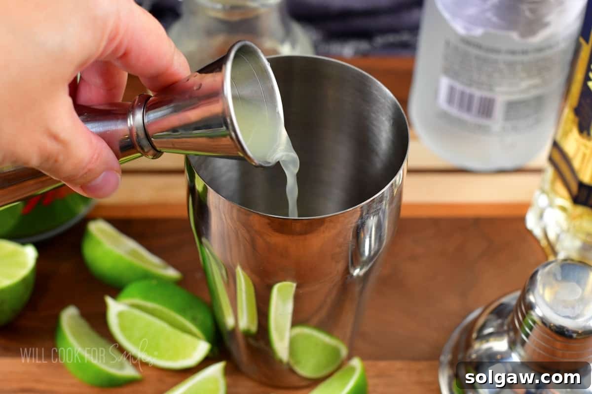 Adding fresh lime juice to a cocktail shaker.