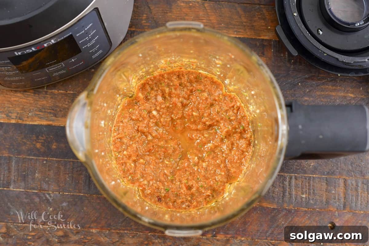 Smooth, vibrant sun-dried tomato pesto freshly blended in a blender, ready to be transferred.