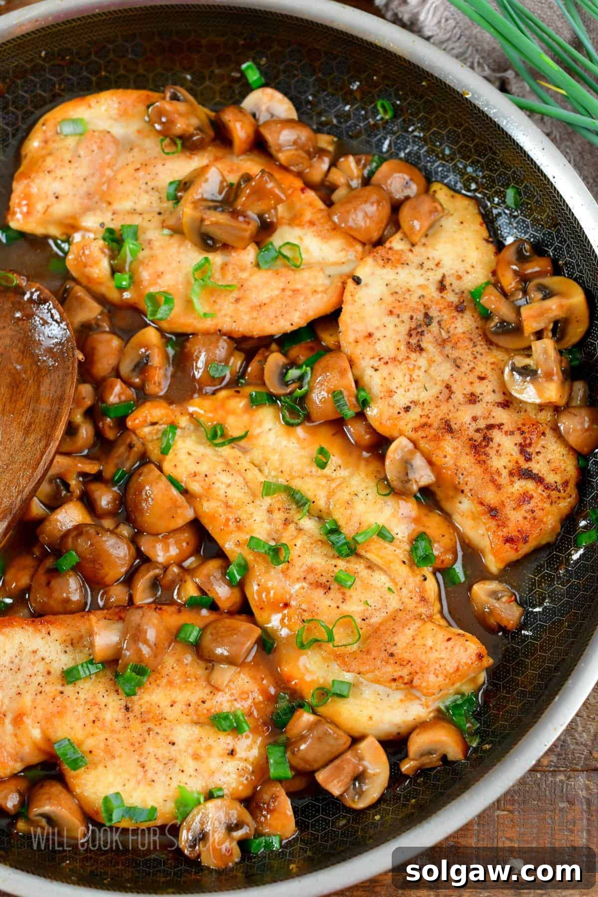 Savory Chicken Marsala 2 Four golden-brown chicken cutlets nestled in a pan with sautéed mushrooms, coated in a luscious Marsala wine sauce, ready to be served.