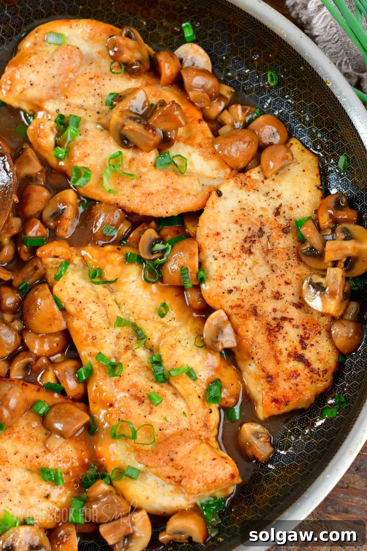Savory Chicken Marsala 8 Three chicken cutlets surrounded by a rich Marsala mushroom sauce in a non-stick cooking pan, ready to be dished out.