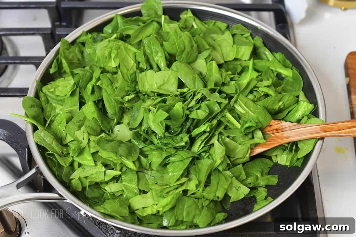 Decadent Cheesy Creamed Spinach 5 Adding a generous amount of fresh spinach to the cooking pan with sautéed aromatics.