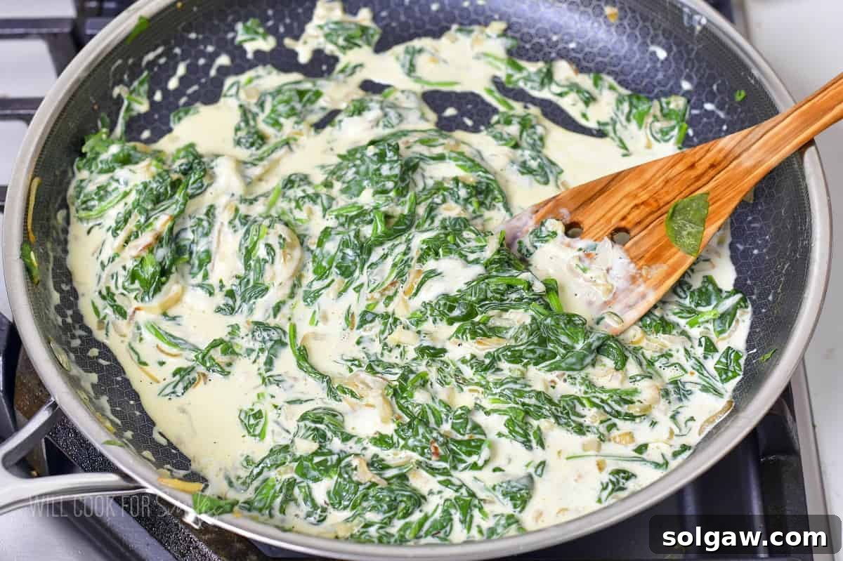 Decadent Cheesy Creamed Spinach 9 Gently stirring the spinach, cheese, and cream together in a pan until fully incorporated and smooth.