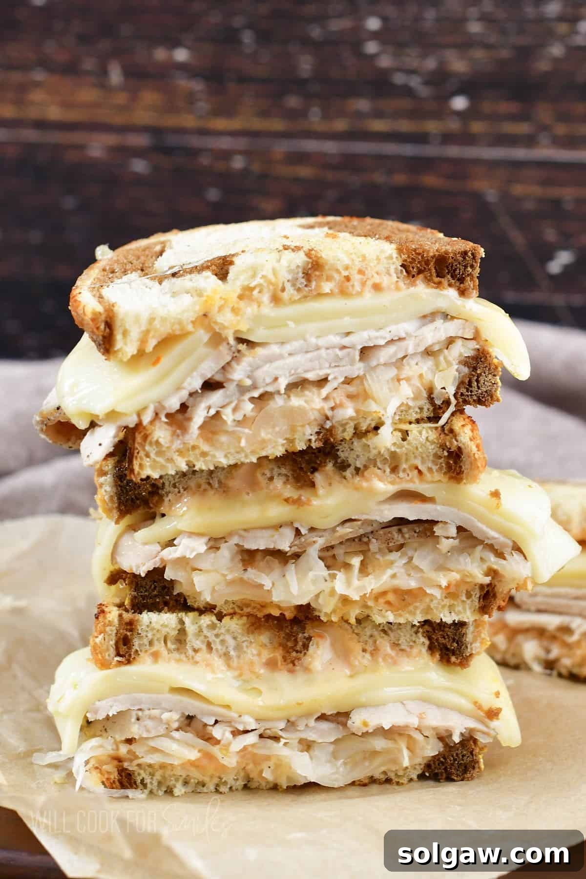 Turkey Reuben Melt 2 Three perfectly grilled Turkey Reuben sandwich halves, stacked and showcasing layers of turkey, Swiss cheese, and sauerkraut between golden rye bread.