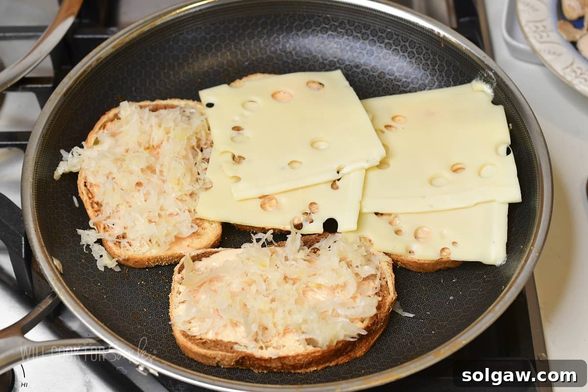 Turkey Reuben Melt 6 Four slices of rye bread in the pan, two topped with Swiss cheese and two with squeezed sauerkraut, preparing for layering.