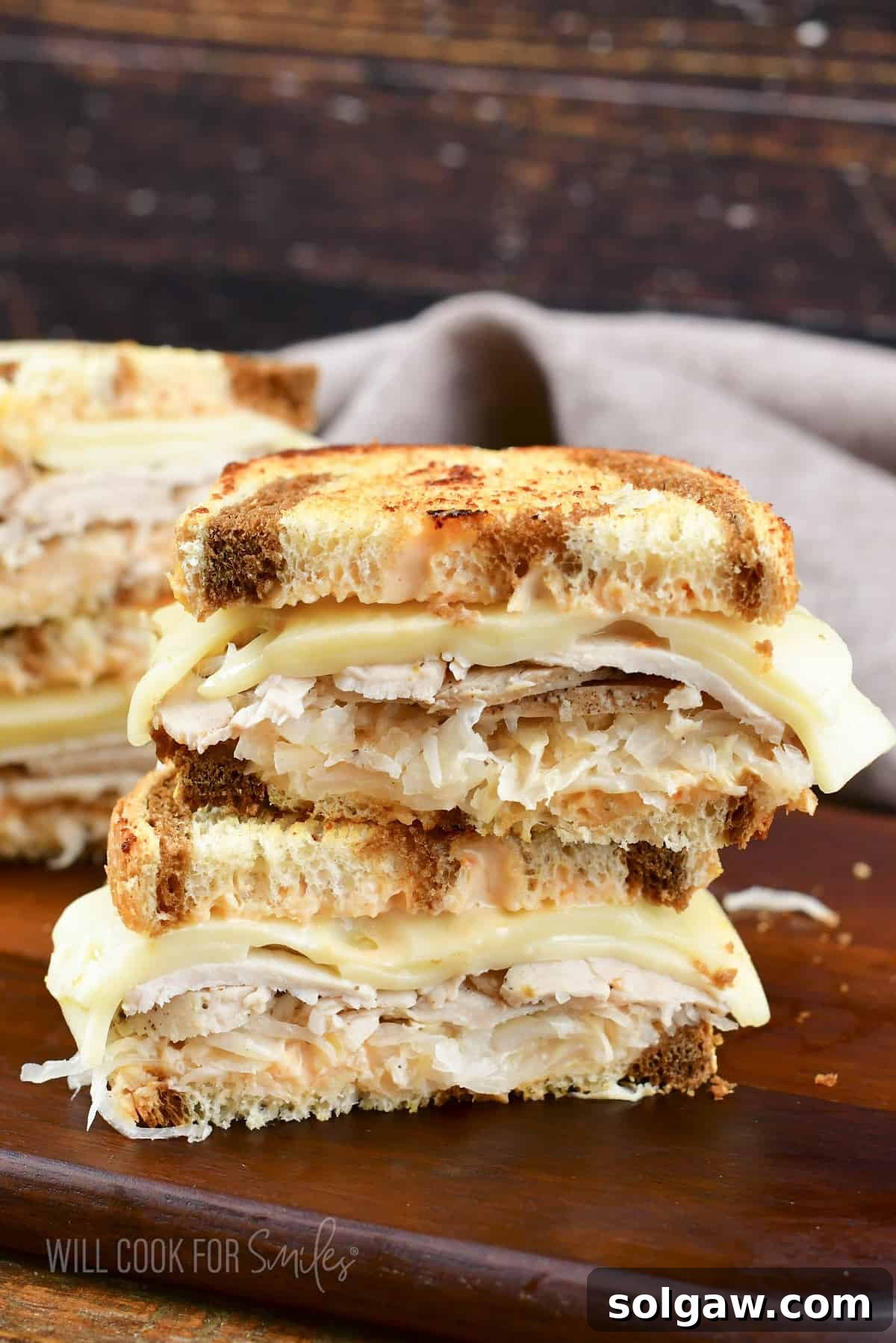 Turkey Reuben Melt 9 Two expertly cut Turkey Reuben sandwich halves, stacked, showcasing the crispy rye bread, melted Swiss, and layers of turkey and sauerkraut.