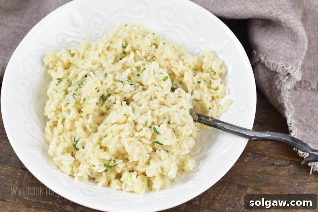 Velvety Parmesan Rice 12 Creamy Parmesan Rice served in a white bowl with a spoon.