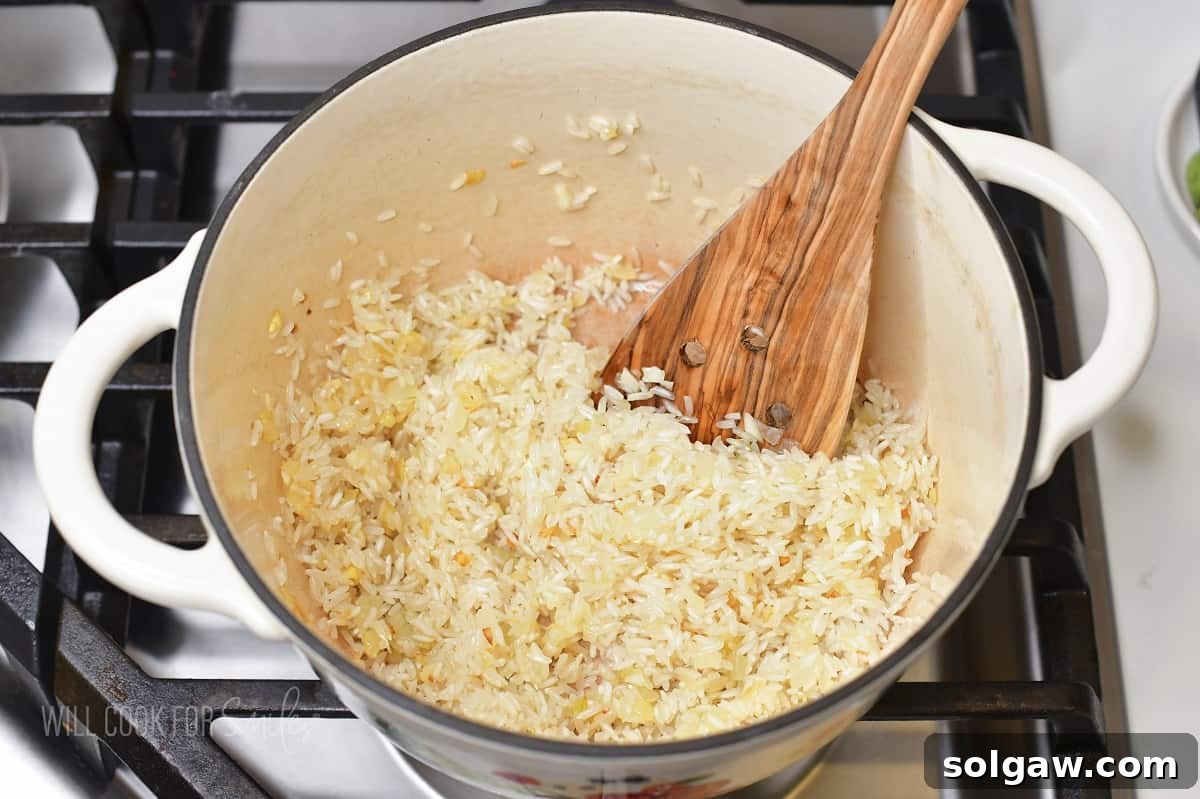 Velvety Parmesan Rice 5 Adding uncooked rice to sautéed onions and garlic in a white pot, stirring to toast.