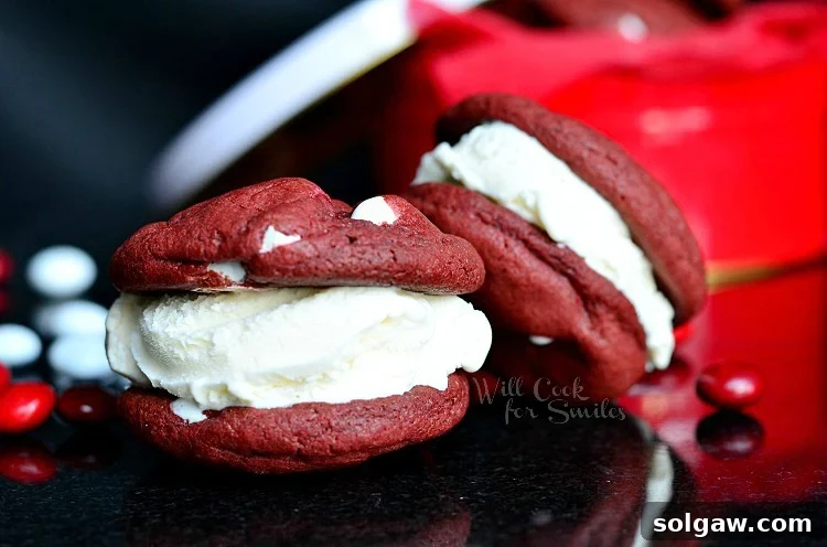 Red Velvet Ice Cream Sandwich Cookies stacked casually on a black countertop, highlighting their inviting texture and rich color.