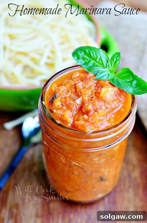 A glass jar filled with homemade Marinara sauce, garnished with fresh basil leaves, sitting on a rustic wooden surface. There's a subtle blur of a kitchen background.